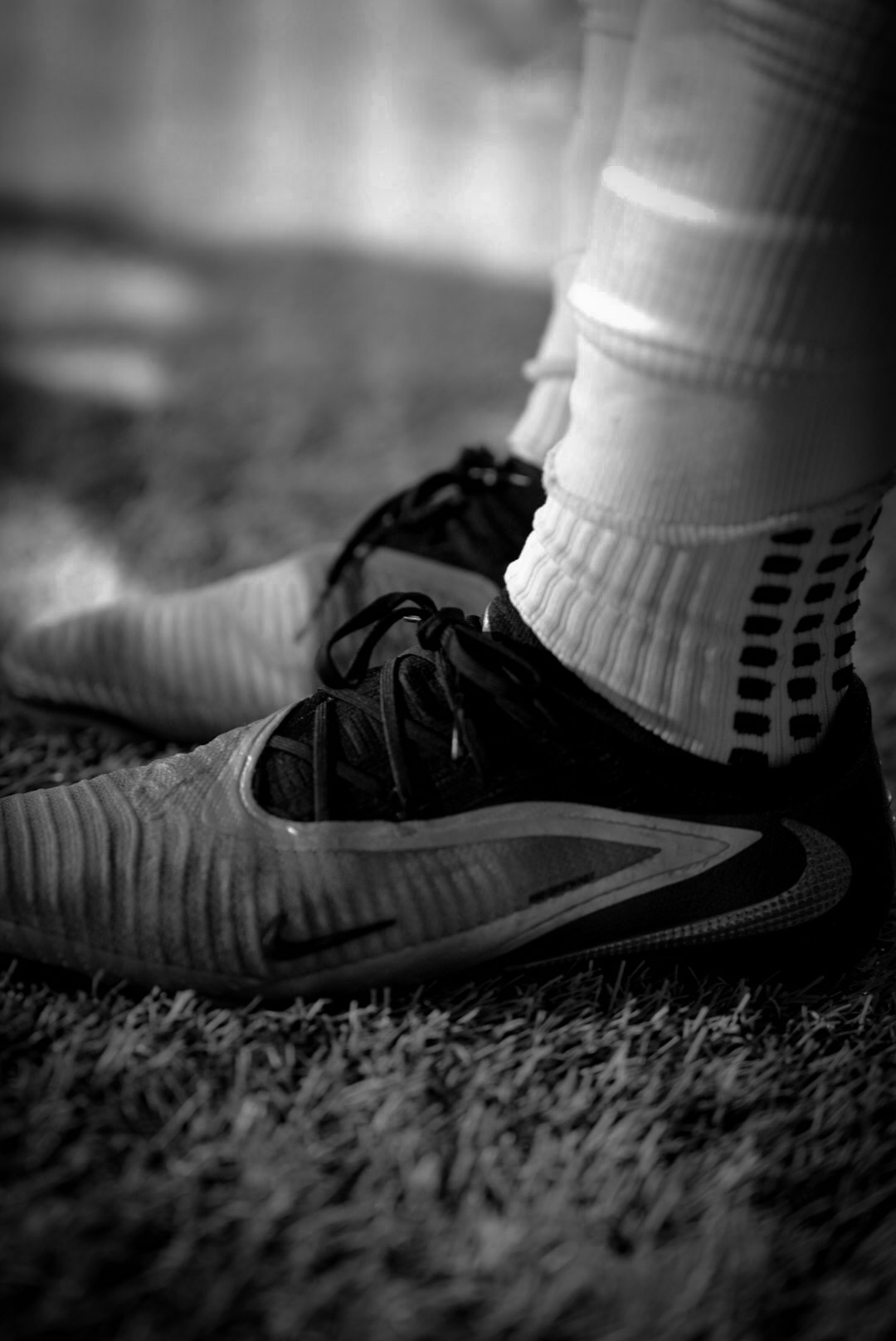 Black and white detail photo of soccer cleats and grip socks on turf